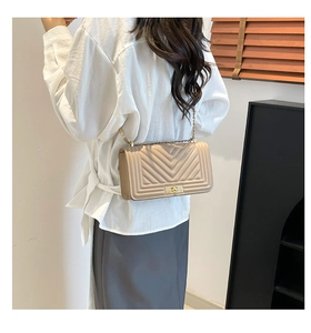 Detail of champagne crossbody bag featuring V-shaped quilting and a gold metal square lock
