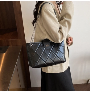 Close-up of black quilted chain tote bag with silver metal swivel lock and glossy finish