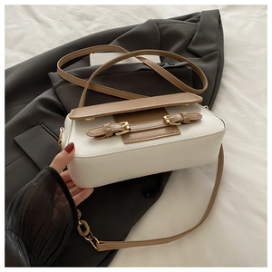 Detail showing contrast khaki leather strap and metal chain on white shoulder bag