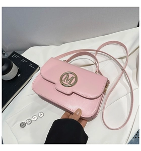 Détail du sac à main en cuir rose avec logo M doré et bandoulière réglable