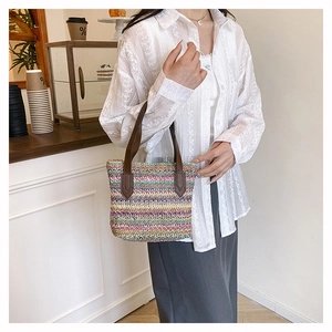 Close-up of colorful woven texture and durable brown leather handles on a beach bag