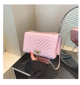 Close-up of pink V-quilted faux leather bag with gold metal clasp and chain strap