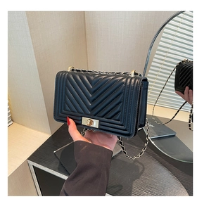 Detail of black chevron quilted leather crossbody bag with vintage gold metal buckle