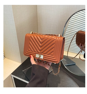 Detail of brown chevron leather bag with golden chain strap and metallic twist-lock