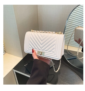 Close-up of white V-quilted shoulder bag featuring a gold clasp and chain strap