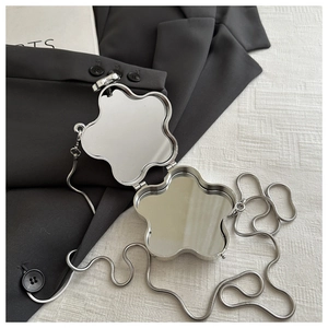 Macro detail of silver flower-shaped pocket mirror with a delicate snake chain