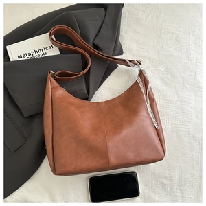 Details der Hobo-Tasche aus karamellfarbenem Leder mit weißem Spitzenband im Fokus