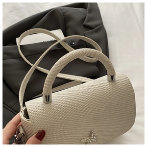 Close-up of beige woven handbag with sparkling rhinestone star buckle and smooth handle