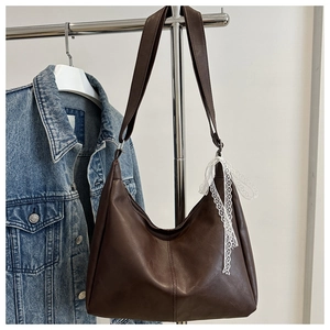 Detailansicht einer dunkelbraunen Shopper-Tasche aus Leder mit weißer Spitzenschleife