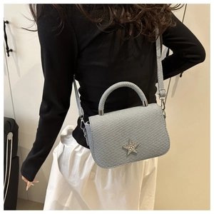 Close-up of light blue textured handbag with a sparkling rhinestone star on the front