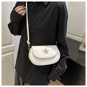 Gros plan d'un sac bandoulière demi-lune blanc avec étoile brillante sur chemise noire