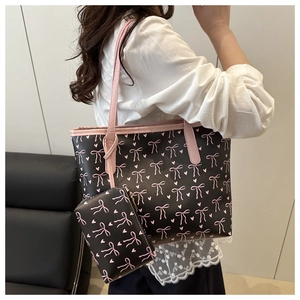 Detail of a large black tote bag with pink bow patterns and a matching small coin purse