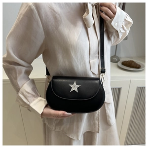 Détail d'un sac besace noir orné d'une étoile argentée scintillante sur le rabat