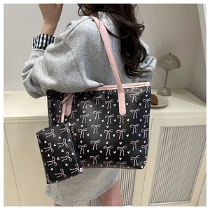 Detailed view of black tote bag with pink bow pattern and matching small pouch