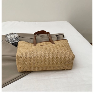 Détail de la texture en paille tressée en V et poignée en cuir marron du sac cabas