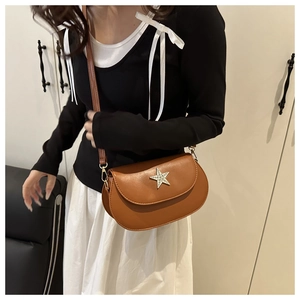 Détail d'un sac besace marron avec un emblème d'étoile en strass et une bandoulière réglable