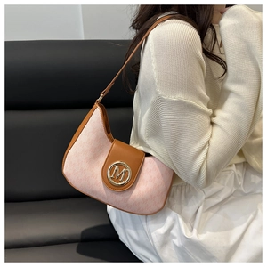 Close-up of pink textured underarm bag featuring a golden M metal buckle and brown leather trim