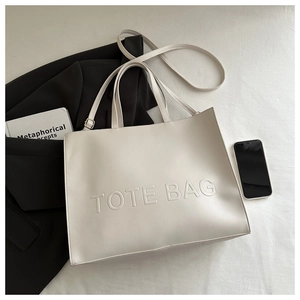 Detail of cream white PU leather tote bag with embossed letters and adjustable strap