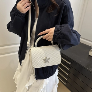 White star crossbody bag with textured finish and silver star detail, shown on model