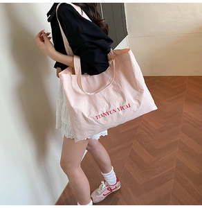 Detail of pink nylon tote bag featuring red letter print and lightweight wrinkled texture
