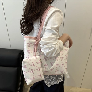 Large tote bag with pink bow pattern and matching pouch shown on woman's shoulder
