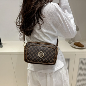 Vintage brown crossbody camera bag with monogram pattern and wide strap on model