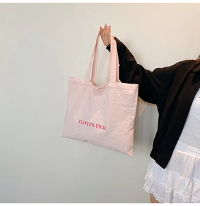 Detail of pink nylon tote bag with red TIANYUN YICAI logo and soft cotton straps