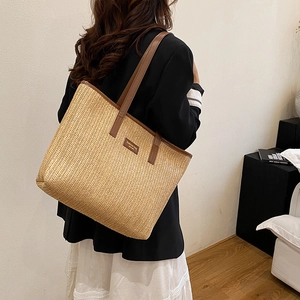 Grand sac cabas en paille tressée avec lanières en cuir marron porté en vue de profil