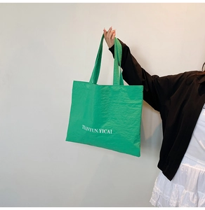Detail of a bright green nylon tote bag with white lettering and sturdy handle