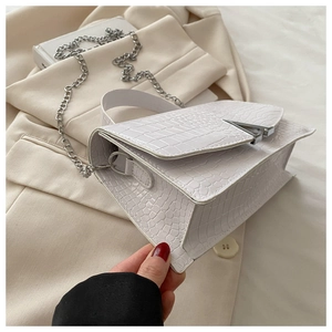 Detail of white crocodile-embossed leather handbag with silver V-shaped metal buckle