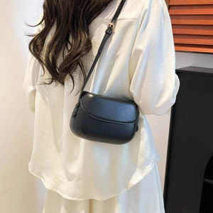 Minimalist black saddle bag for women featuring matte leather and gold adjustable strap