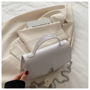 Detail of white crocodile texture handbag with silver A-letter buckle and chain