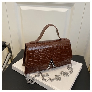 Detailed macro view of brown crocodile texture leather handbag with silver A-shaped clasp