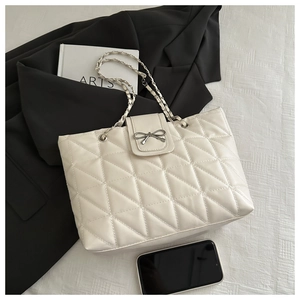 Détail d'un sac cabas matelassé blanc crème avec fermoir nœud argenté et chaîne