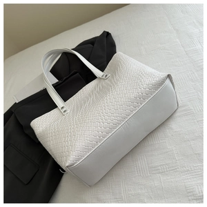 Dettaglio della borsa tote intrecciata bianca con borchie argentate sulla tracolla