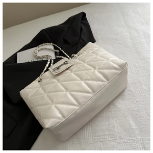 Détail d'un grand sac cabas matelassé beige avec nœud argenté et bandoulière en chaîne