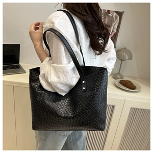 Dettaglio della grande borsa tote in pelle intrecciata nera indossata da una modella