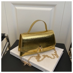 Detail of gold crocodile texture handbag with V-shaped metal buckle and chain strap