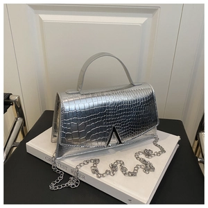 Close-up of silver crocodile-embossed handbag with V-shaped metal lock and chain strap