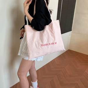 Pink large capacity nylon tote bag with TIANYUN YICAI logo worn on shoulder