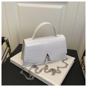 Detail of white crocodile texture handbag with silver V-shaped lock and metal chain strap