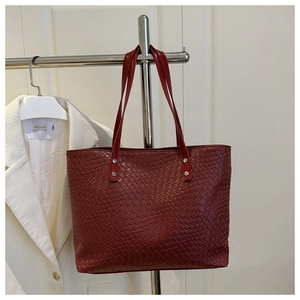 Dettaglio della trama intrecciata della borsa tote rosso scuro con manici in pelle