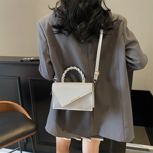 Chic silver square handbag with glitter flap and twisted handle worn with a grey suit