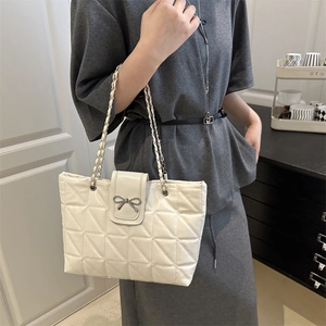 Sac bandoulière matelassé blanc avec fermoir nœud et chaîne porté par un modèle