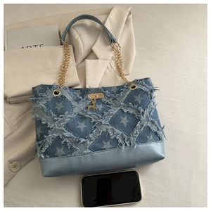 Blue denim tote bag detail featuring frayed star patterns and a gold deer charm accessory