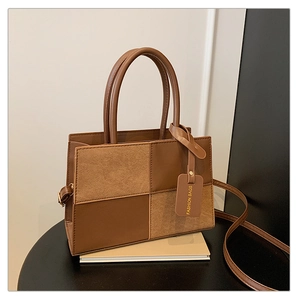 Detail view of the brown color-block handbag with textured leather and suede materials
