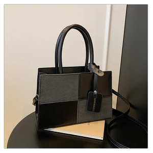 Detail of color-block PU leather handbag with detachable strap and logo tag accessory