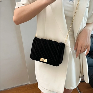 Borsa a tracolla in velluto nero con catena e trama trapuntata su abito bianco