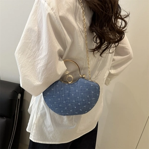 Blue denim half-moon shoulder bag with golden ring handle and chain strap on model