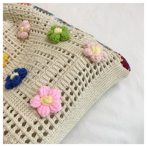 Detailed close-up of handmade 3D floral crochet on a beige knit shoulder tote bag